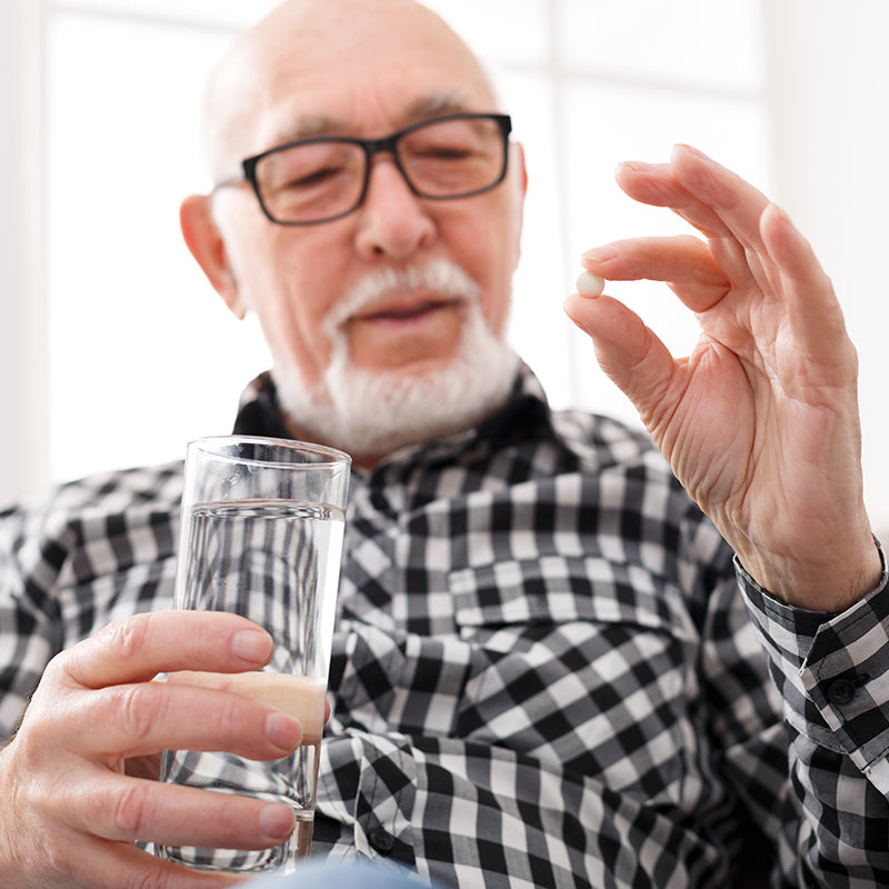 Old man having a glass of water and pills in hand